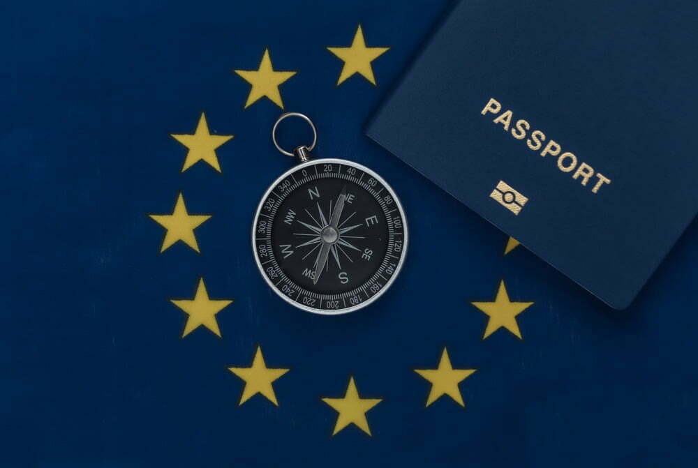 Compass and passport on EU flag close up. Top view